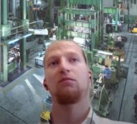 Industrielle Fertigungshalle mit Maschinen und Arbeitern bei der Produktion.